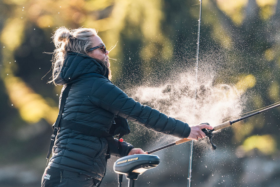 Evelina Henriksen i svart täckjacka och solglasögon på sin båt, sportfiskar.