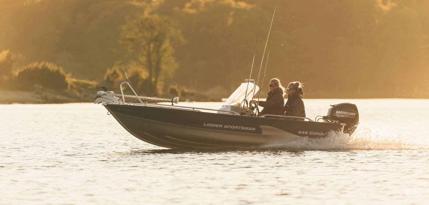 Två sportfiskare kör en fiskebåt från Linder. Ljuset är disigt som tidig morgon. Bilden tagen från sidan.