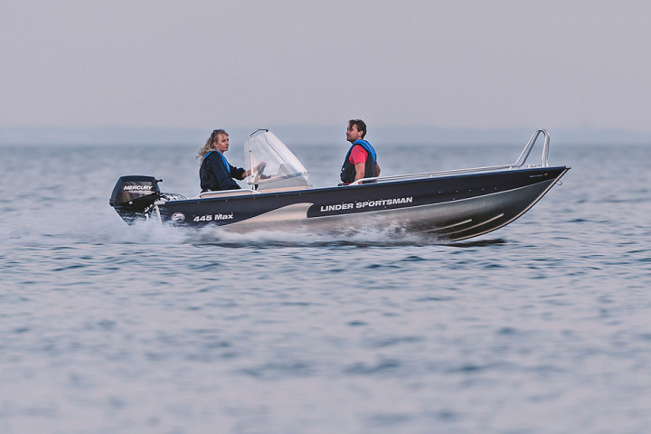 Båten sportsman 445 max körs på sjön av två personer. Gråsdisig dag.
