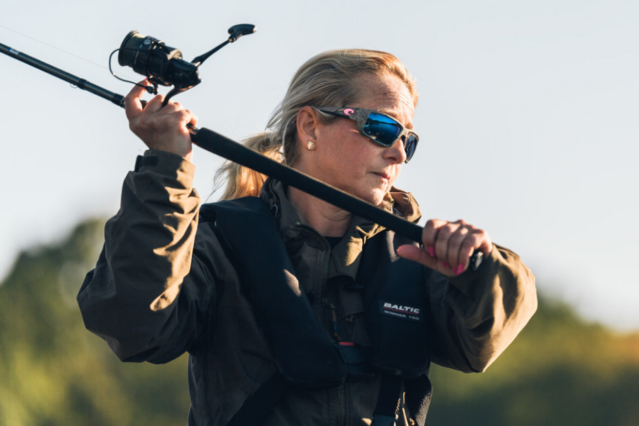 Sportfiskare Ella Micalsen i brun jacka och solglasögon gör ett spökast.